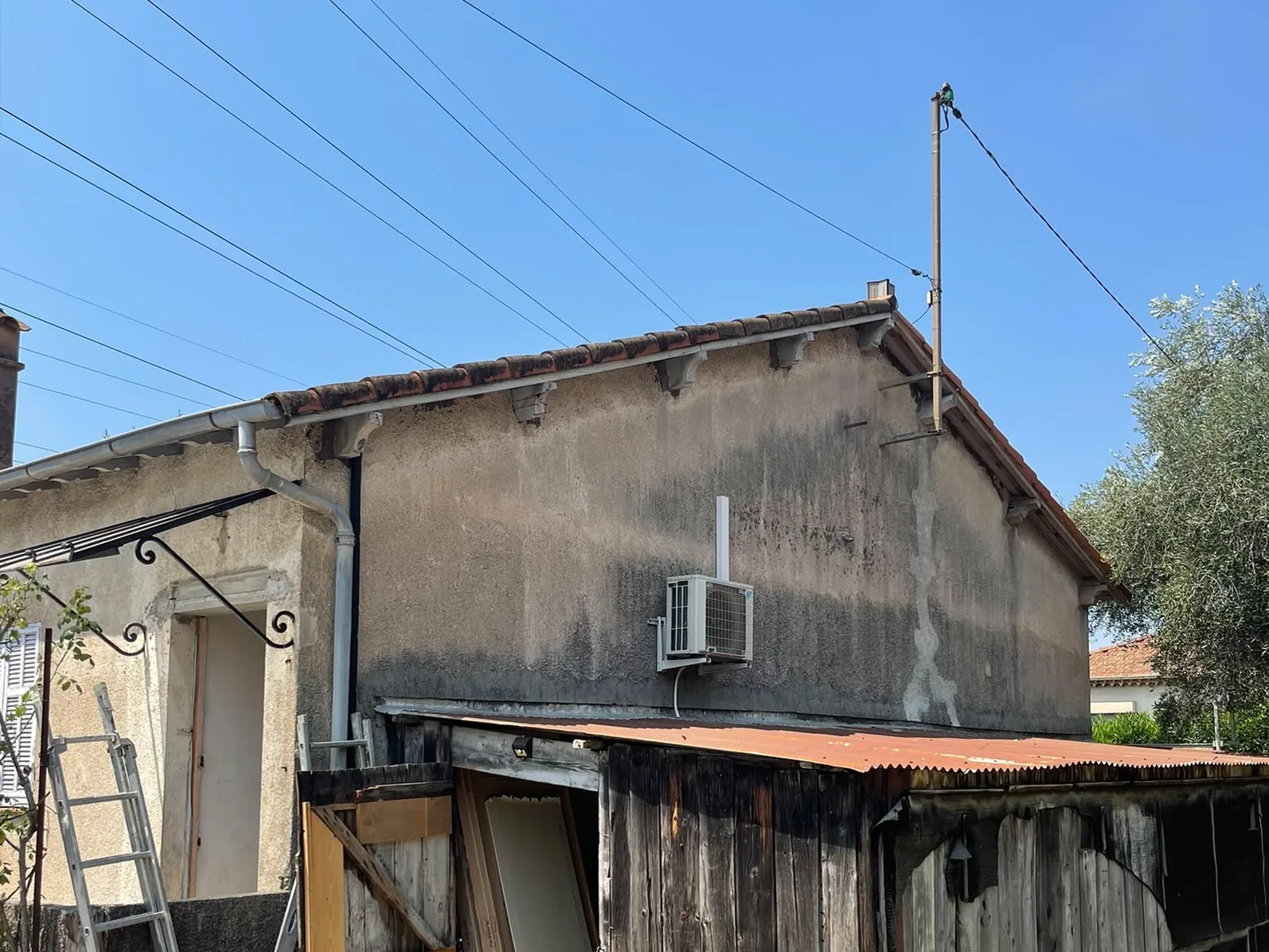 Appentis en bois adossé au pignon arrière, mur noirci par l’humidité