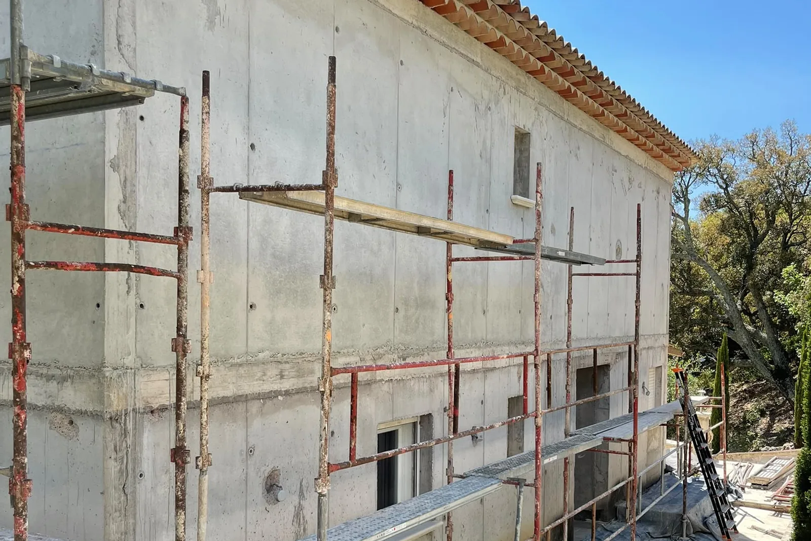 Longue façade en béton banché avant enduit, sous échafaudage